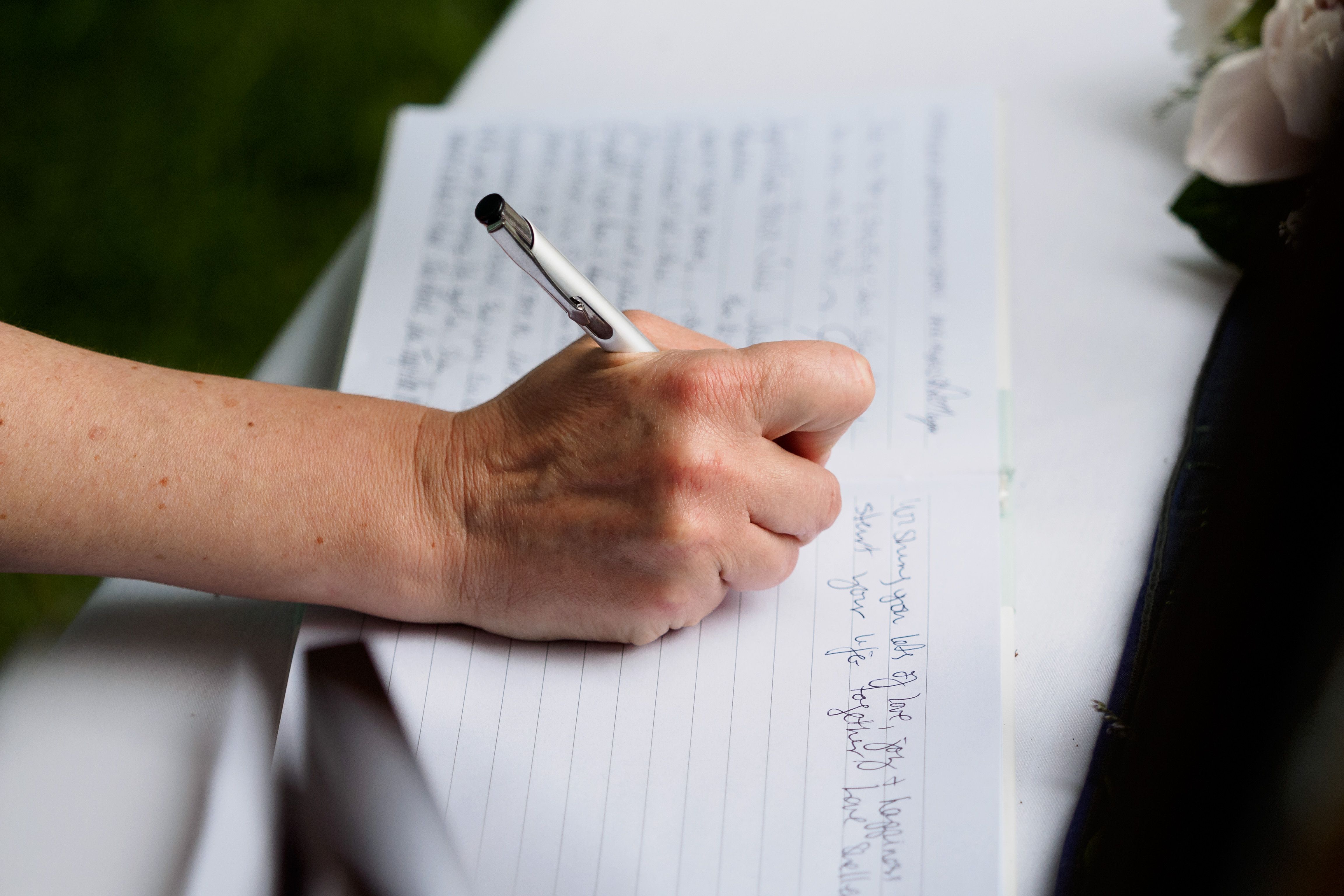 Invitada escribiendo una dedicatoria en un libro de firmas durante la boda