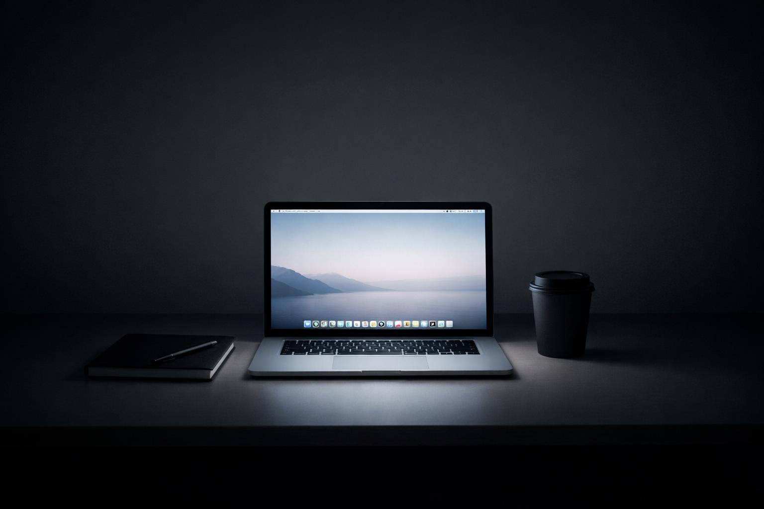MacBook planning app on a tidy desk beside a notebook and closed coffee cup, emphasizing focused work