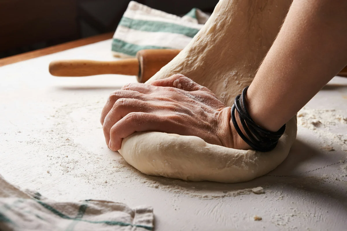 Manos que amasan pan en la cocina de un comercio