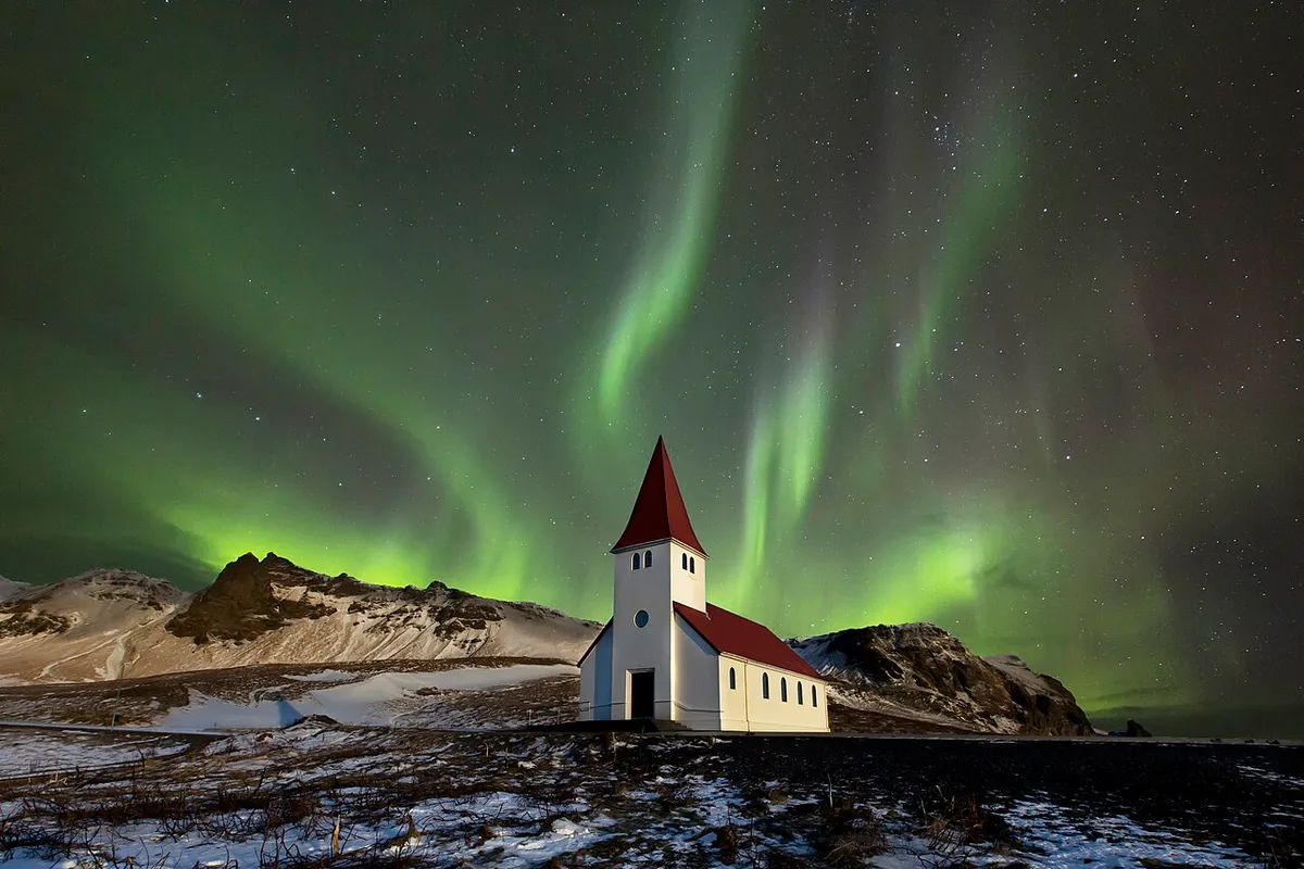 Photomontage - The Víkurkirkja church at Vik in Iceland on a clear night. The aurora was shot separately in Iceland (see File:Flames in the sky.jpg).