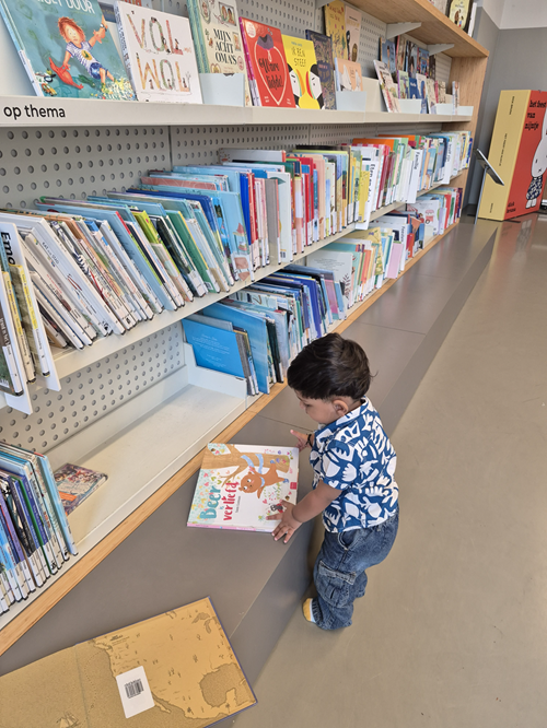 Toddler browsing picture books inside Utrecht Library