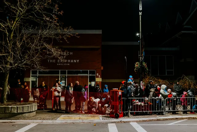A crowd lines a barricaded street outside Church of the Epiphany Anglican at night.