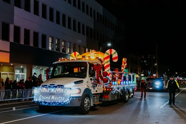 The Grand Marshal truck, lit in white and blue, moves along the route.