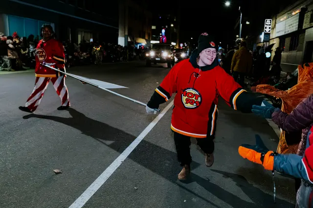 A child in a hockey jersey runs across the street ahead of the parade.