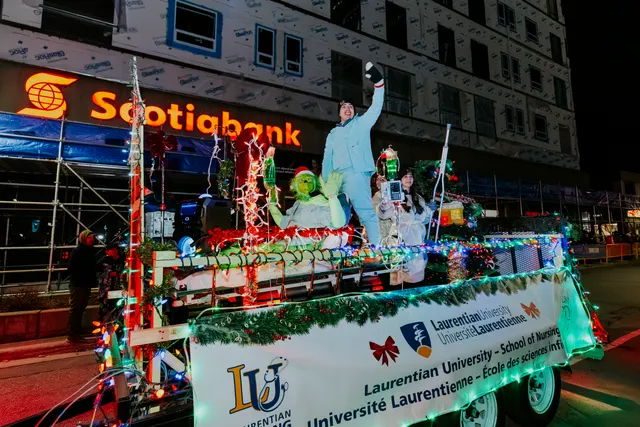 A Grinch-costumed rider waves atop a lit float for Laurentian University’s School of Nursing.