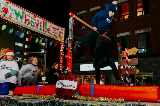 A gymnast leaps over a giant candy-striped obstacle on a Whoville-themed float.