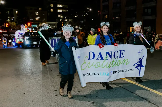 Dancers carry a Dance Evolution banner reading 'Dancers light up our lives'.
