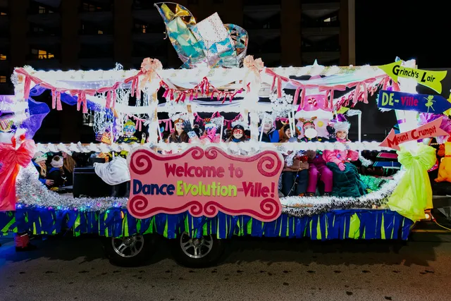 A colorful Whoville-themed float reads Welcome to Dance Evolution-Ville, with costumed dancers aboard.