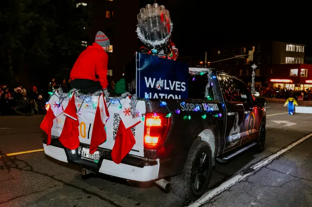 A pickup truck decorated with red stockings displays a Wolves Nation banner in the parade.