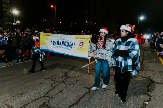 Marchers in checkered ponchos and Santa hats carry a banner reading Colombia.