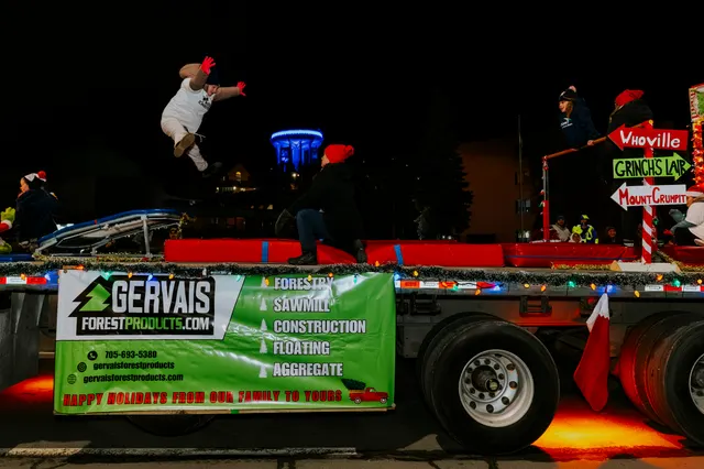A performer flips through the air off a padded ramp on a Gervais Forest Products float.