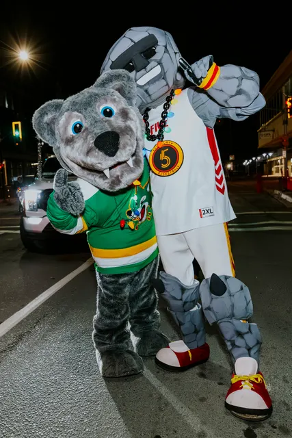 A wolf mascot in a hockey jersey greets the crowd along the route.