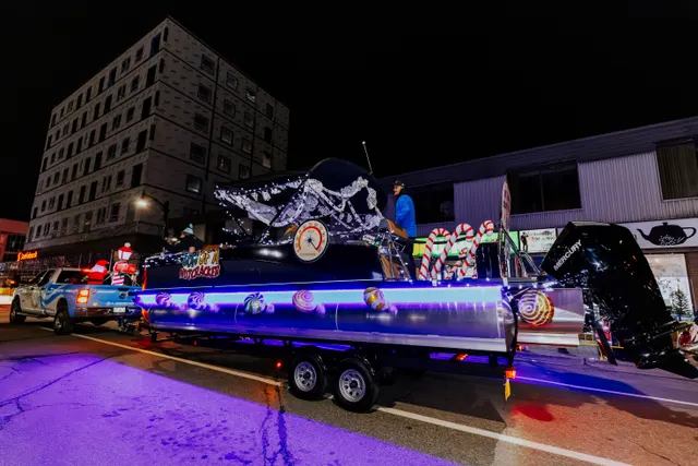 A boat-shaped float painted with an orca design glows under blue and purple lights.