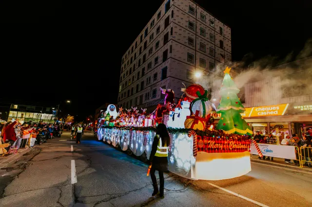 Lit floats stretch down the street at the end of the parade, snow blowing through the light.