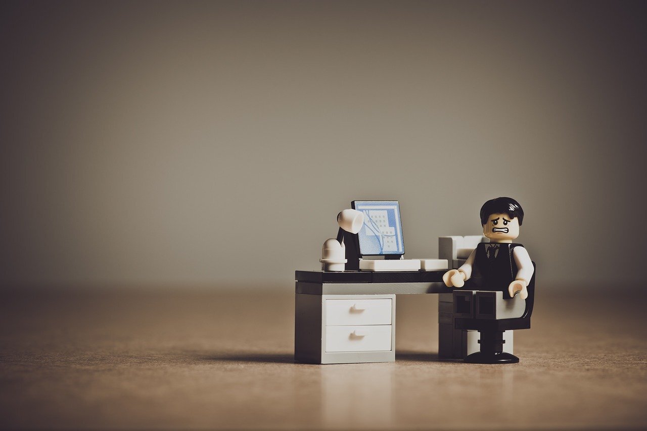 Lego character at a desk showing an expression of needing help