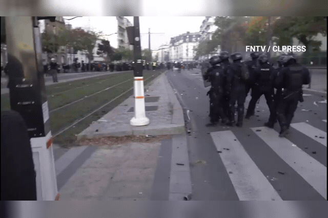 A device thrown at Paris police explodes, setting an officer's leg alight near Porte de Charenton, as at least 300 arrests were made across France by Saturday afternoon.