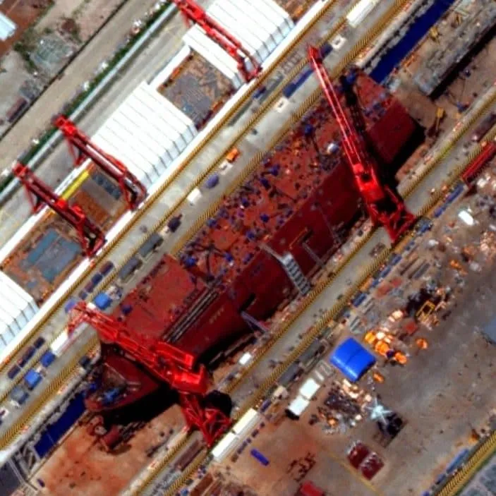 Satellite photographs of Shanghai's Hudong-Zhonghua Shipyard show the vessel features an internal forward hangar and a wet-well deck with 12 vertical lifting arms to lower drones into the water.
