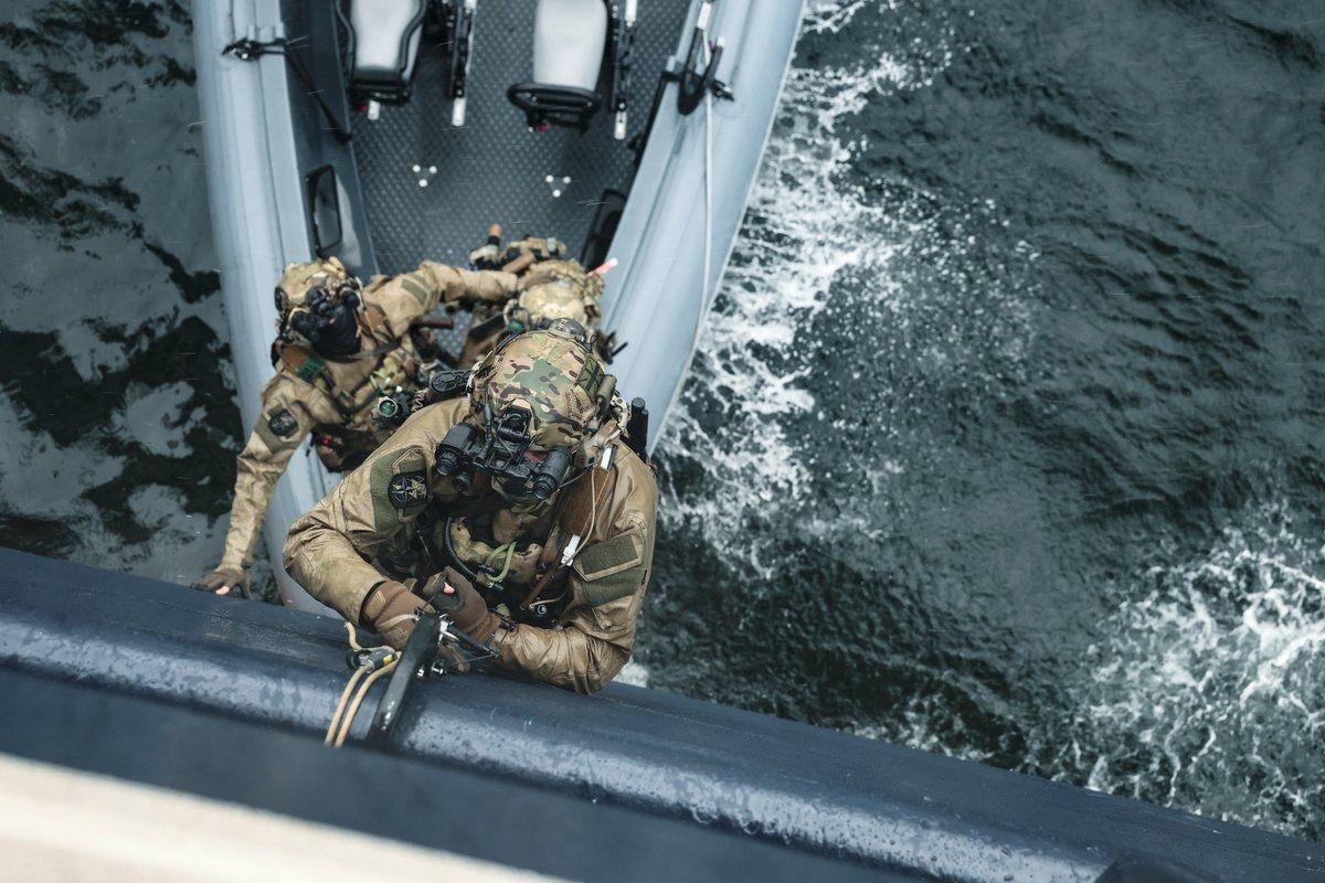Royal Marines climbing from a rigid inflatable boat onto a vessel in the Faroe Islands, as Exercise Lion Protector 26 spans the North Atlantic, High North and Baltic Sea.