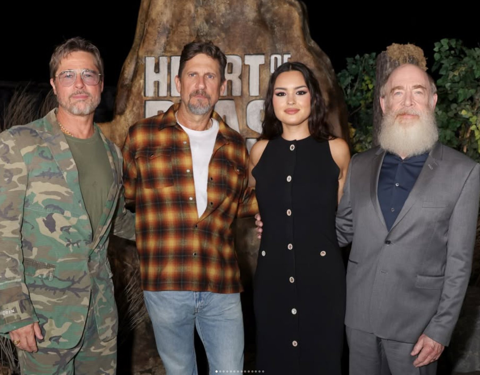 Brad Pitt (left), whose camouflage suit at the 'Heart of the Beast' premiere drew comparisons to a Spirit Halloween costume, with colleagues at the film event.