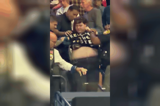 A woman in a 'Release the Epstein Files' shirt is removed from Donald Trump's Youngstown rally by attendees and police, after a supporter who punched her in the face remained inside exchanging high-fives.