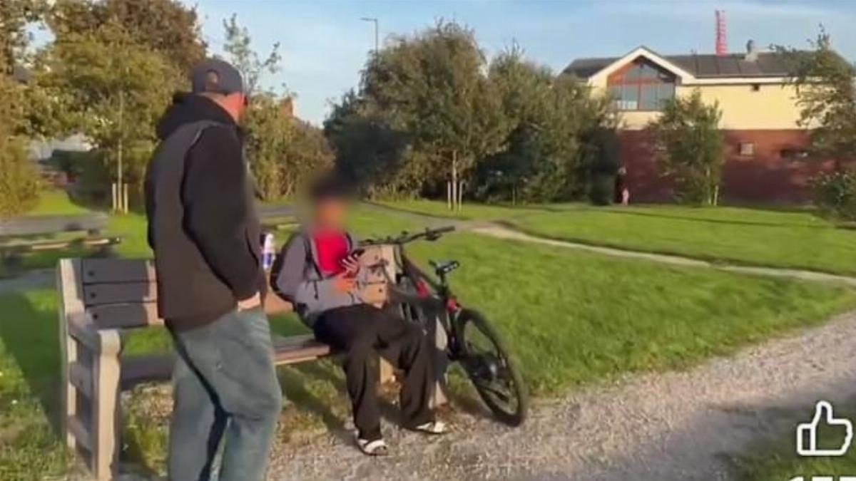 A young black man sits on a bench at Thornton village green, his bike beside him, as members of a self-styled 'Patriot Patrol' group order him to leave — with one carrying a Red Bull can telling him nearby women did not…