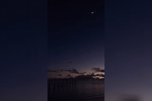 A luminescent jellyfish-shaped cloud spreads across the Florida sky, an effect visible only during dusk or dawn launches when sunlight strikes the frozen upper-atmosphere plume at just the right angle.