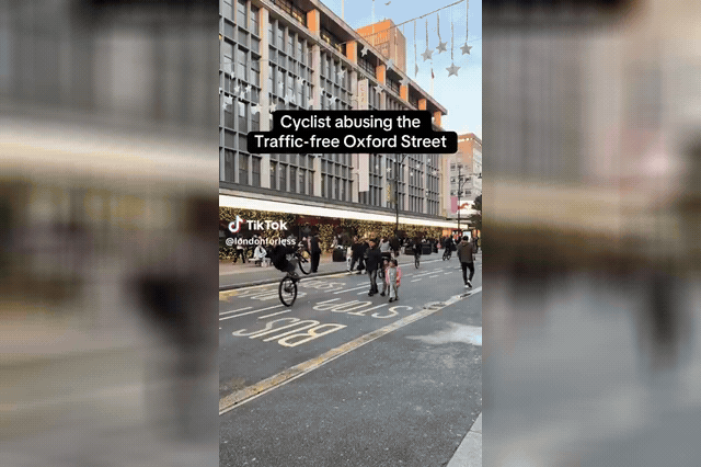 A cyclist blasts past a security guard standing with arms outstretched at the bollards on Oxford Street, as riders were filmed mocking helpless guards unable to enforce the pedestrianisation ban.