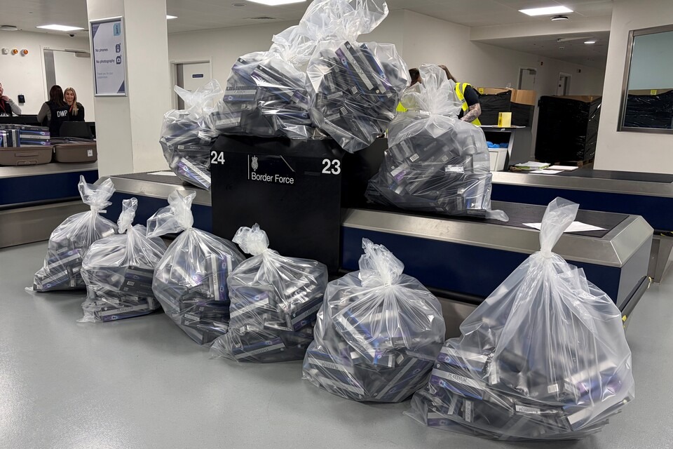 Bags of seized cigarettes at a Manchester Airport Border Force examination belt, where officers intercepted nearly five million illicit cigarettes — including 100,000 on a single Dubai flight — plus 405kg of rolling…