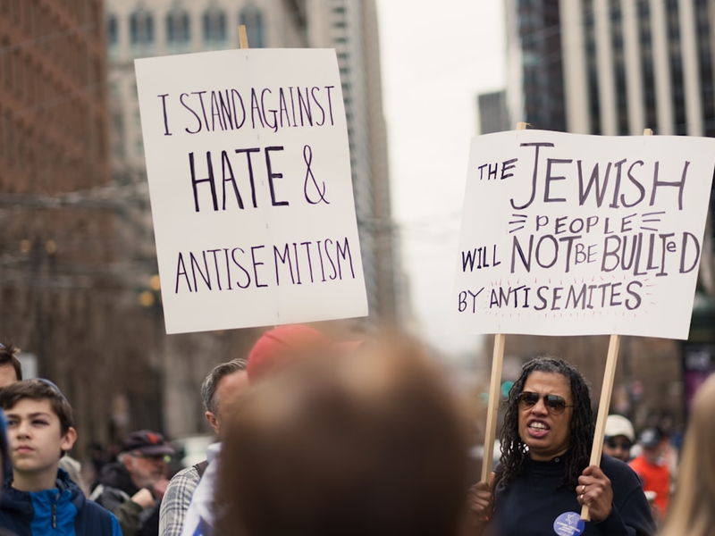 People hold up signs stating "I STAND AGAINST HATE & ANTISEMITISM" AND "THE JEWISH PEOPLE WILL NOT BE BULLIED BY ANTISEMITES" at the Unity Rally, a march against antisemitism in San Francisco.