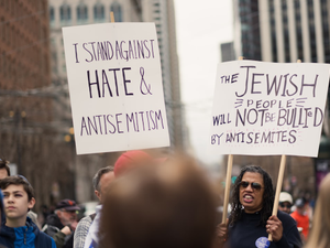 People hold up signs stating "I STAND AGAINST HATE & ANTISEMITISM" AND "THE JEWISH PEOPLE WILL NOT BE BULLIED BY ANTISEMITES" at the Unity Rally, a march against antisemitism in San Francisco.