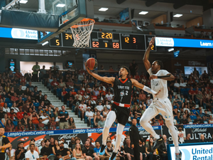 Basketball player shoots the ball over an opponent.