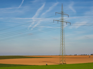 A huge electricity pole on an brown agriculture field,shot from a public place.