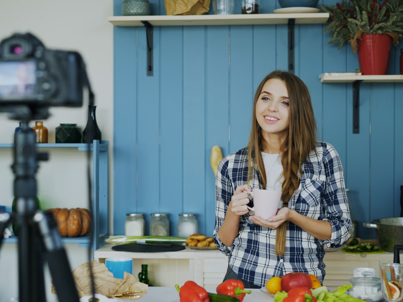 Young attractive woman recording video food blog about cooking on dslr camera in kitchen at home