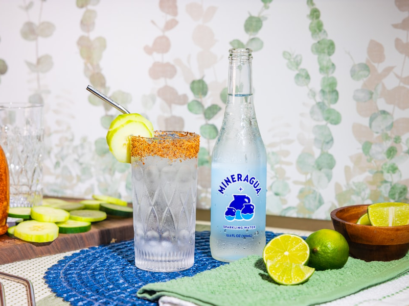 a table topped with bottles of alcohol and a bowl of limes