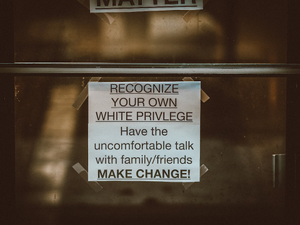a sign on a door that says, recognize your own white privilege have the uncomfortable