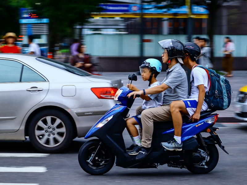 three people riding blue motor scooter