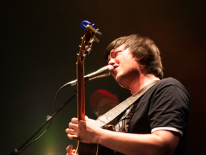 man singing on microphone while playing guitar