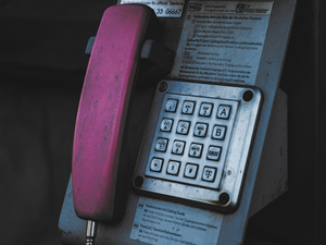 An old style phone is attached to a wall