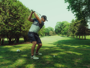 A golfer is swinging his club on the course.