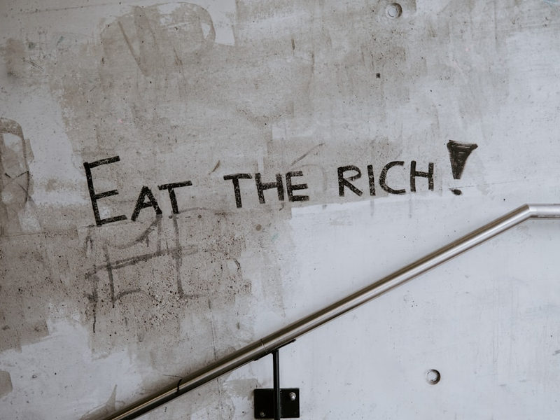 graffiti on a wall that says eat the rich