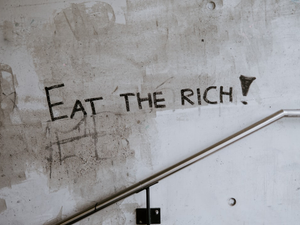 graffiti on a wall that says eat the rich