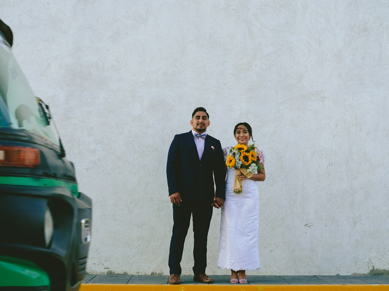 man in black suit standing beside woman in white wedding dress