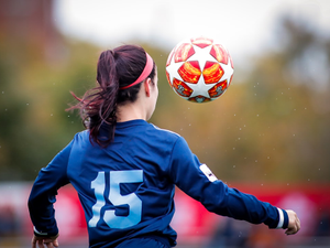 Young women with eyes focused on the soccer ball while controlling it during a girl football match.