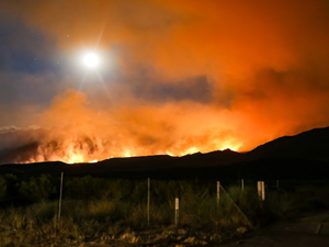 California wildfire with glowing orange smoke in the Sierra Nevada mountains.