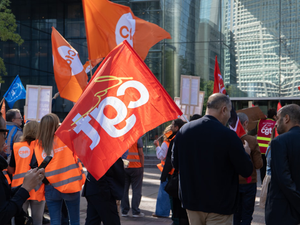 People holding red and orange flags at a rally.
