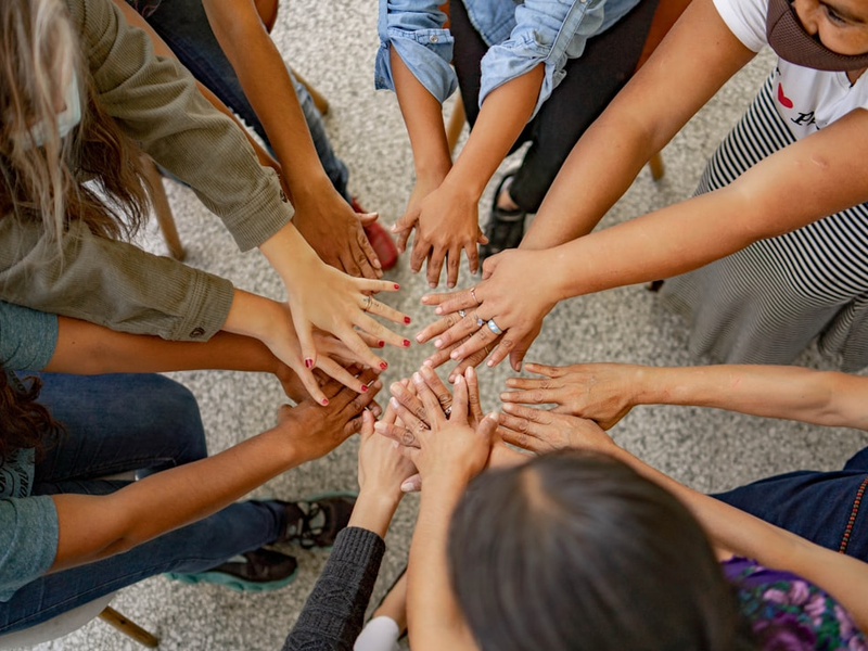 A group of people standing in a circle with their hands together