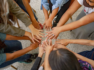A group of people standing in a circle with their hands together