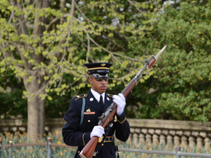 man in black and brown camouflage uniform holding rifle