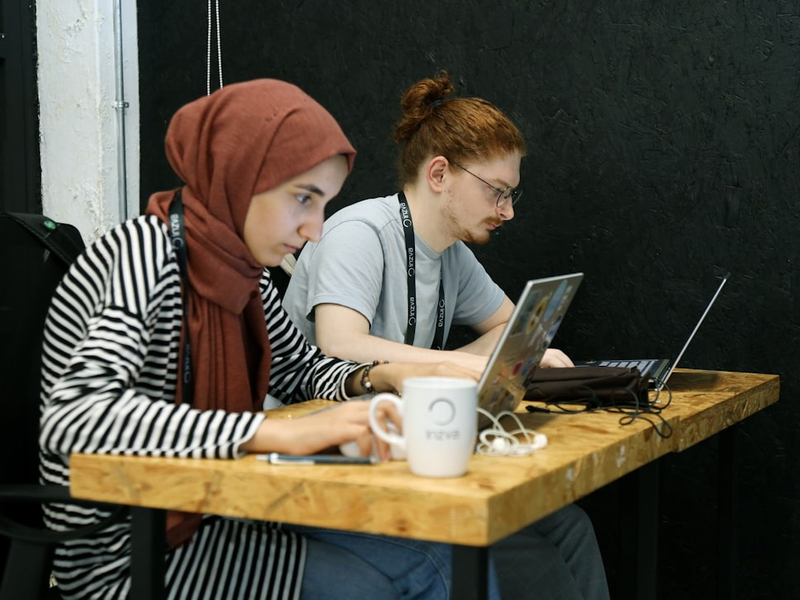 two women sitting at a table with laptops
