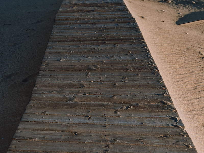 A weathered wooden walkway through sand dunes